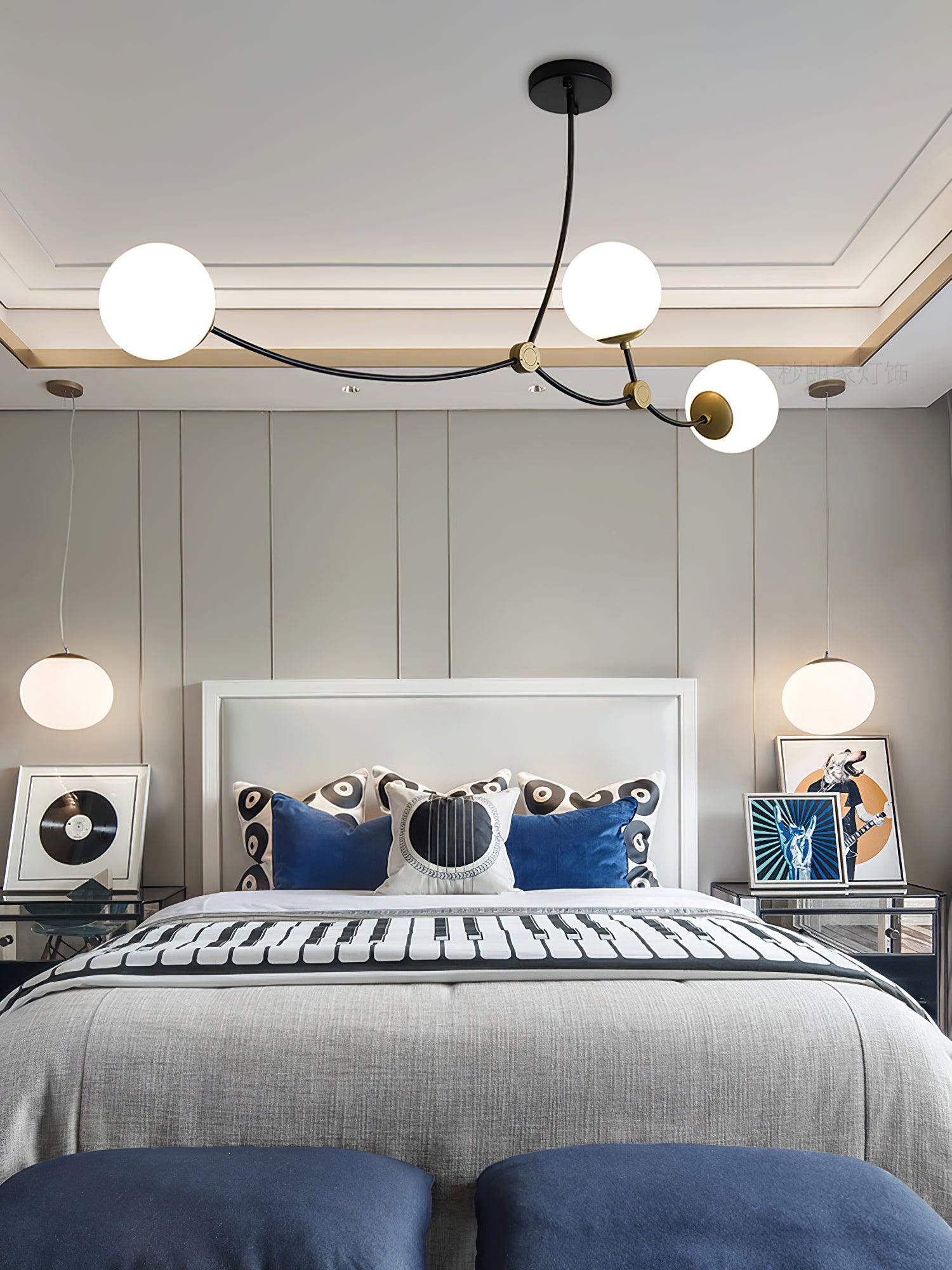 Three-globe chandelier above a bed