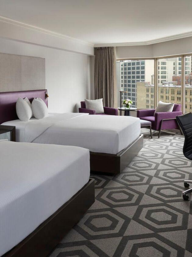 Small reading light at the edge of a purple headboard in a twin bedroom