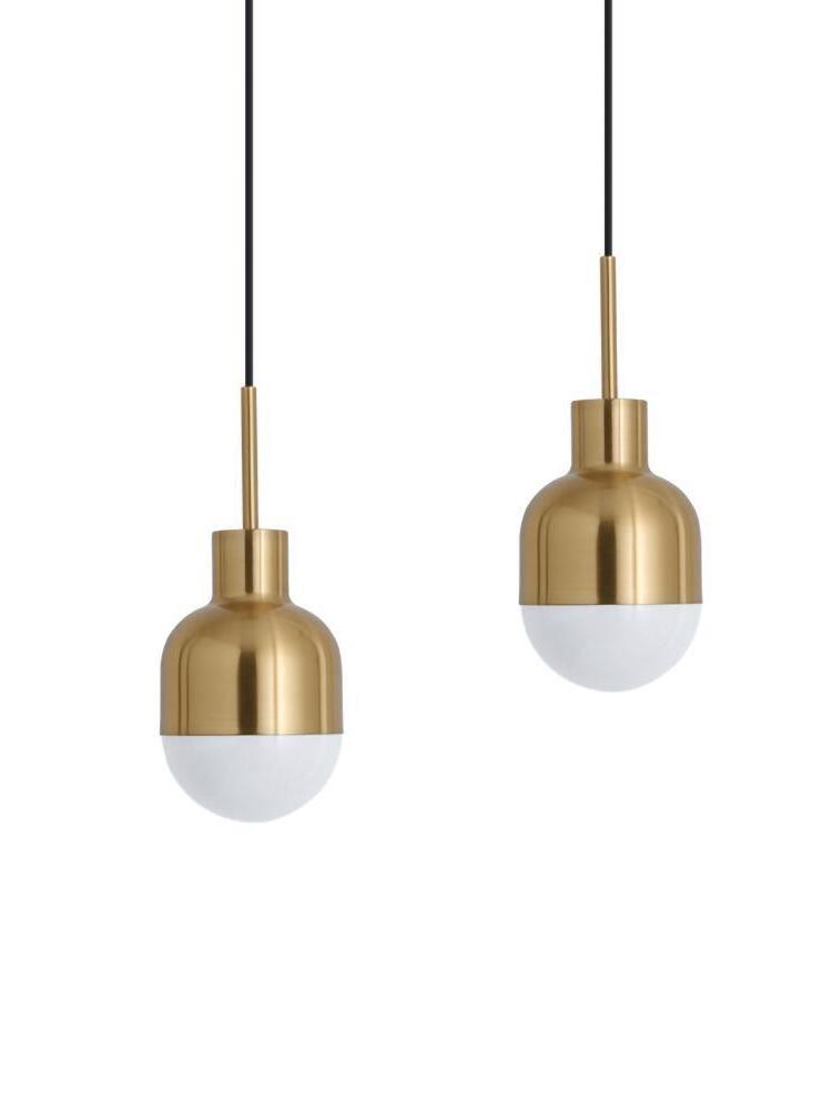 Two separate Niku pendants at different heights against white, with gold-tone housings and white lower globes