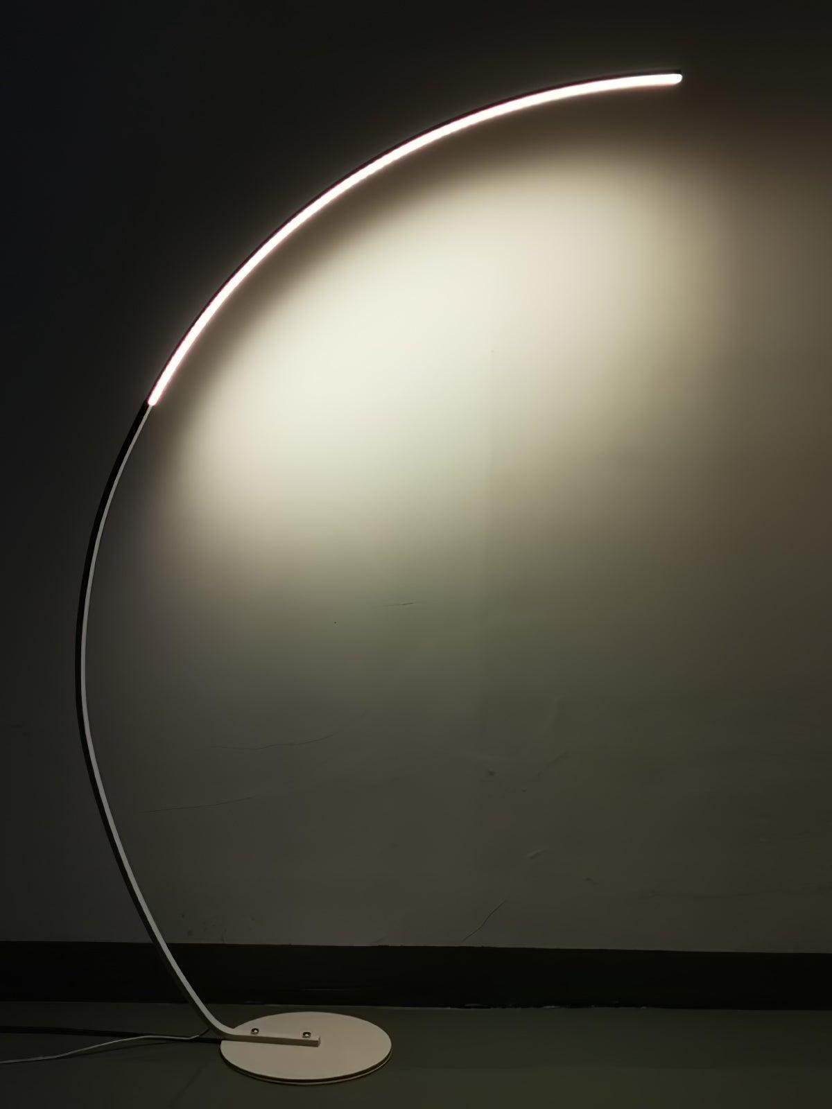 White arc floor lamp lit against dark background