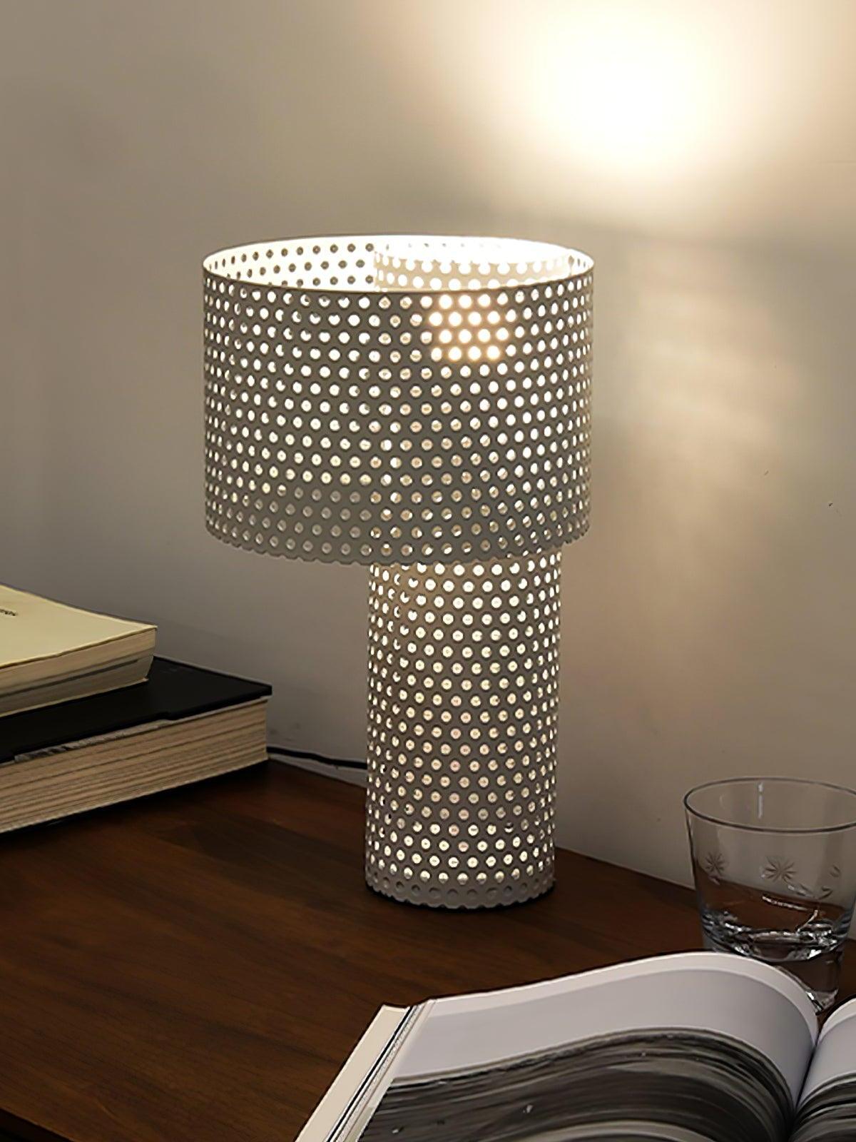 White perforated lamp beside stacked books on wooden desk