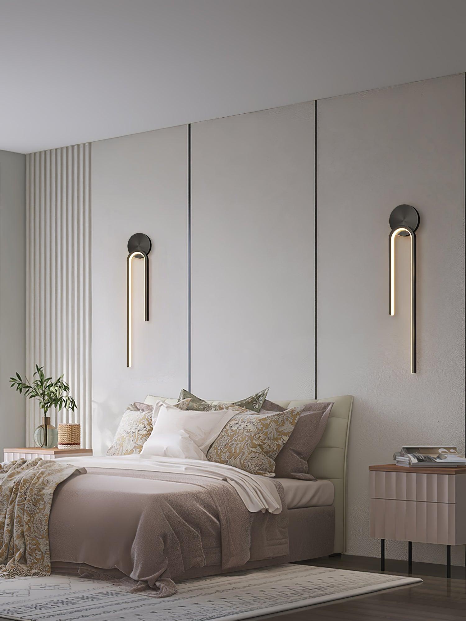 Two dark arch wall lights above bedside cabinets on either side of a bed with patterned pillows