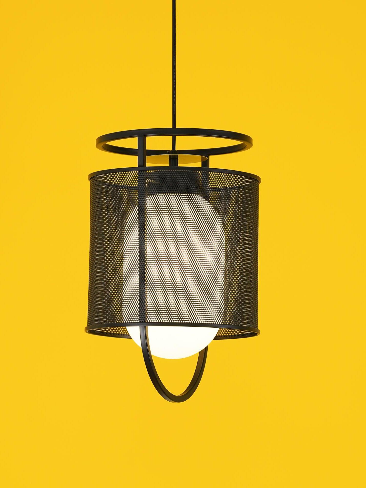 Single black hanging lantern against bright yellow background
