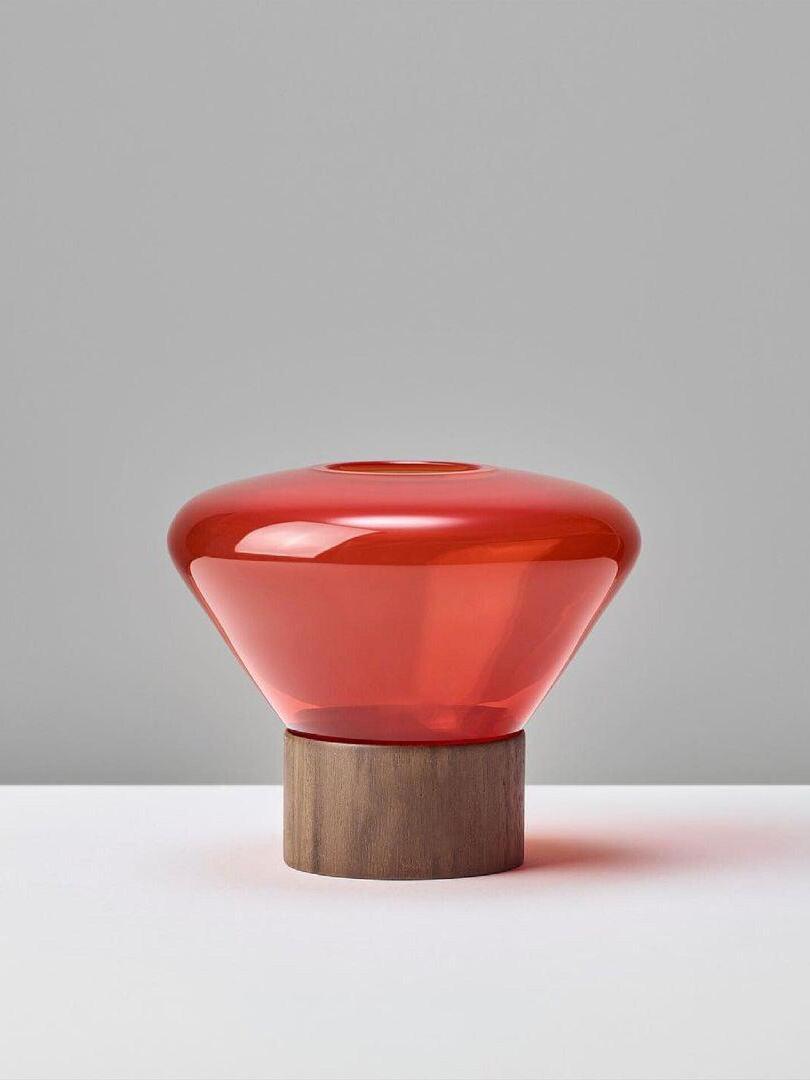 Isolated vivid red rounded glass shade with top opening on dark wood base