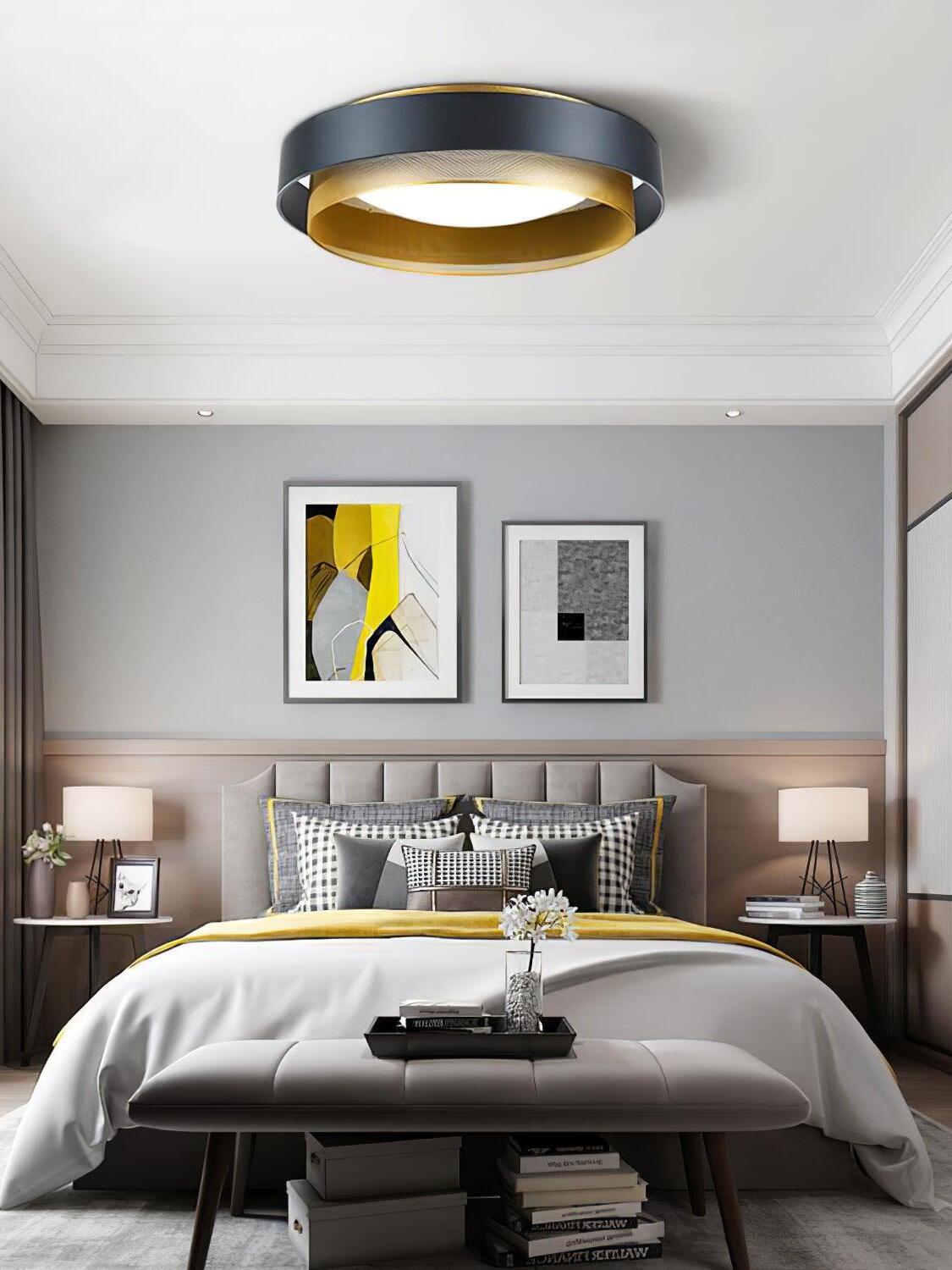 Black and gold Nolan ceiling light above a bed with framed artwork and bedside tables