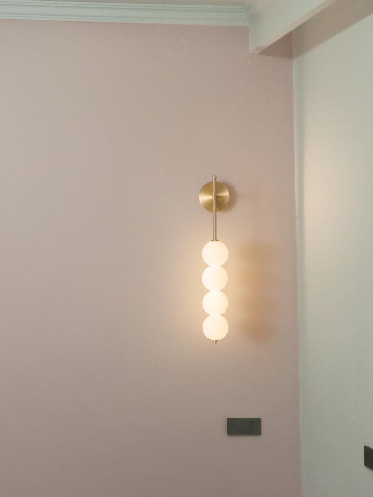 Brass globe wall light on a pale pink wall