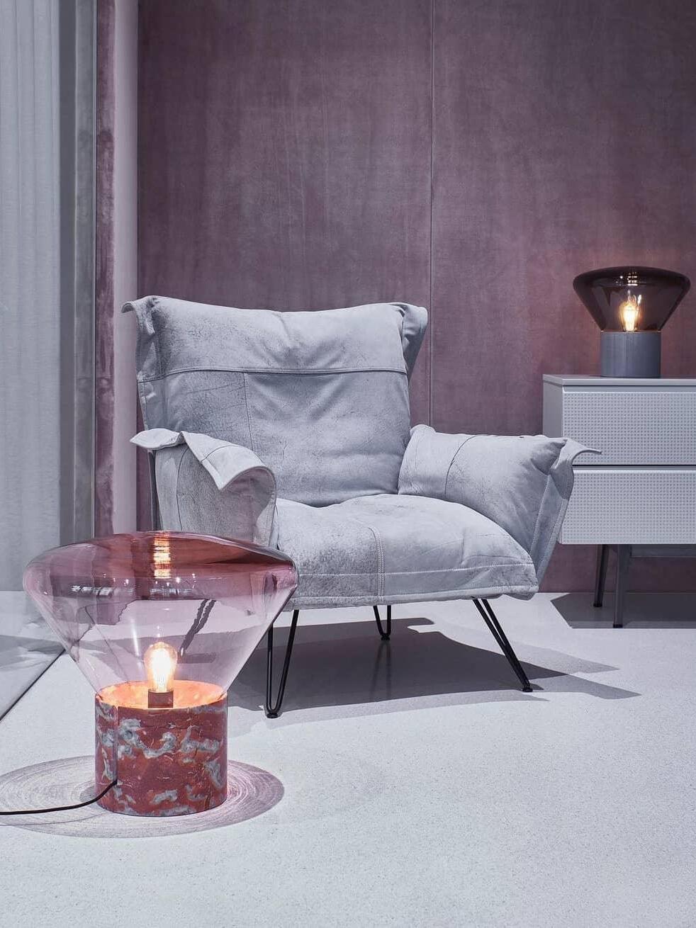 Pale pink glass lamp with red marbled-looking base near upholstered chair