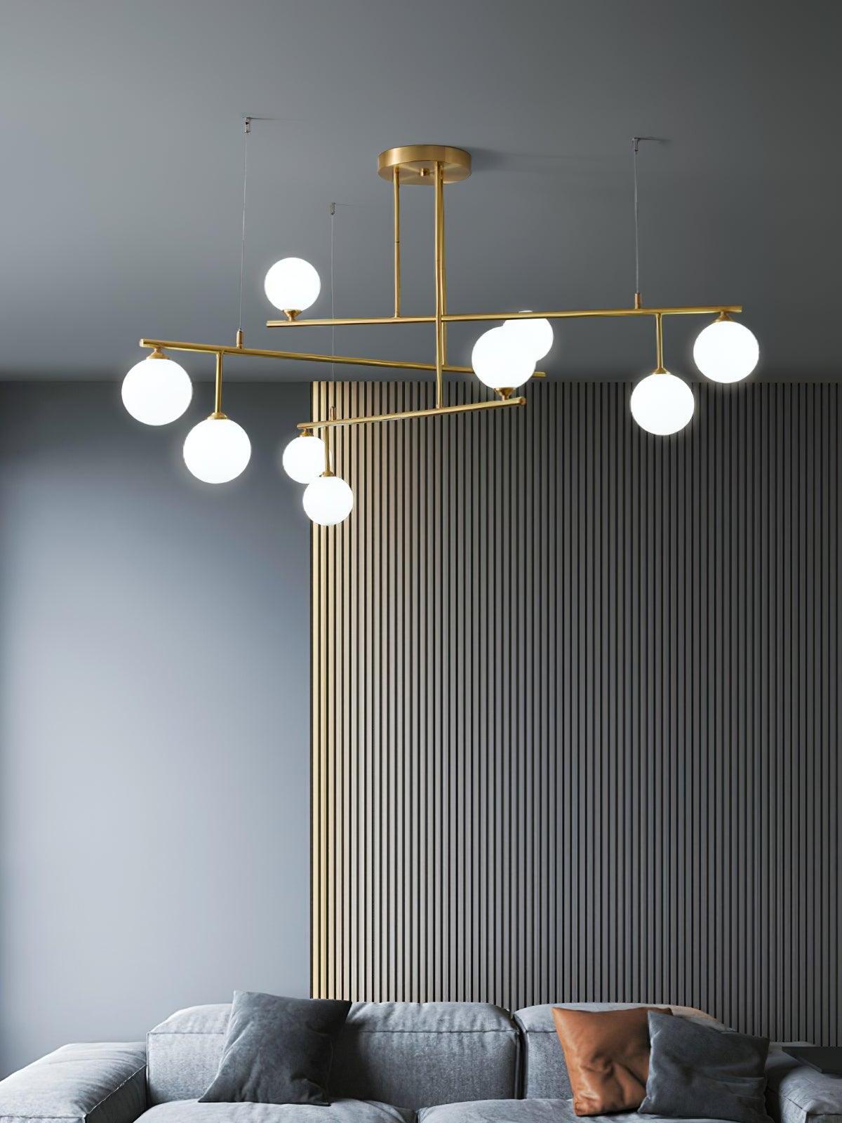 Tiered Arteriors globe chandelier over a grey sofa with a rust-coloured cushion and vertical wall panels