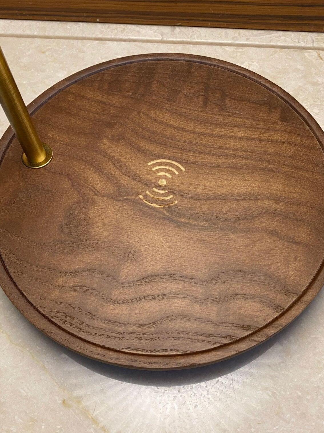 Top view of the round dark wooden base with visible grain, a recessed rim and a wireless-style symbol