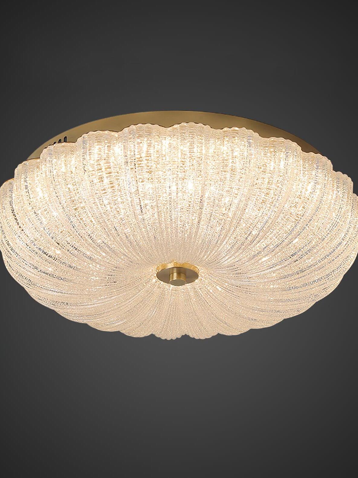 Fluted glass ceiling bowl with a warm-looking glow, scalloped edge and gold-tone finial