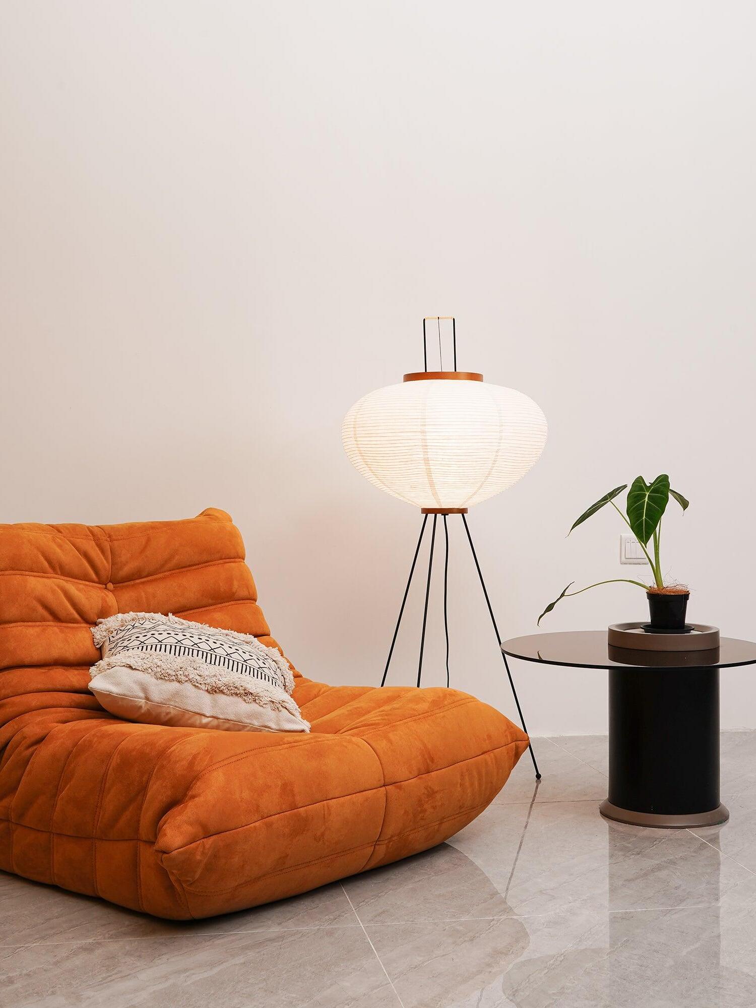 Rounded paper floor lamp beside orange sofa