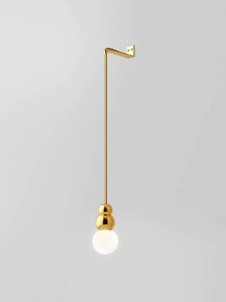 Gold Rod wall light with larger glowing round bulb