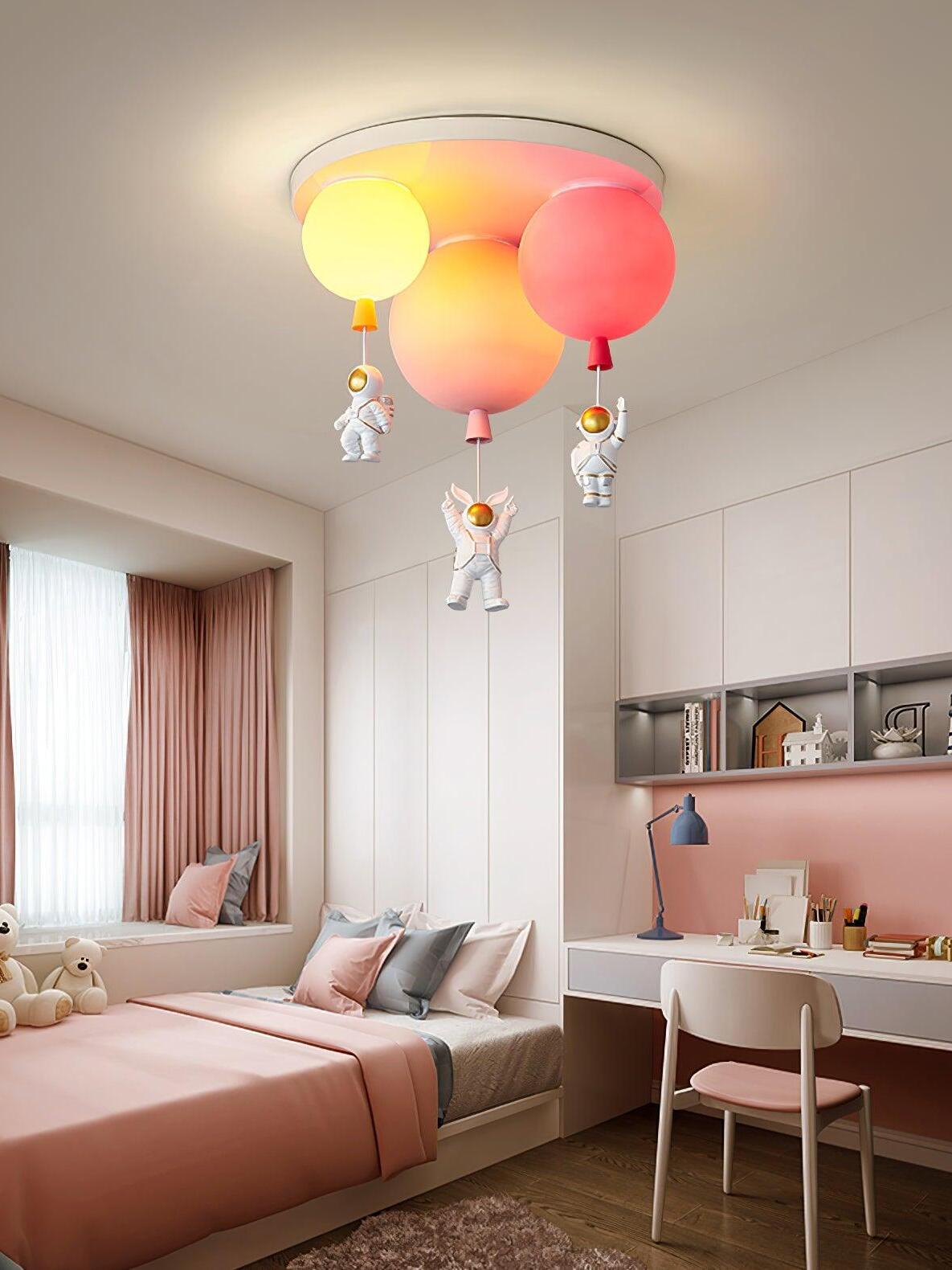Illuminated balloon shades above a pink bed and desk