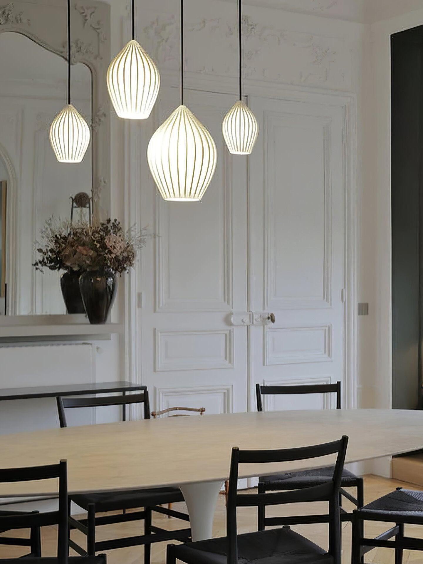 Four ribbed ceramic pendants at staggered heights above a wooden dining table