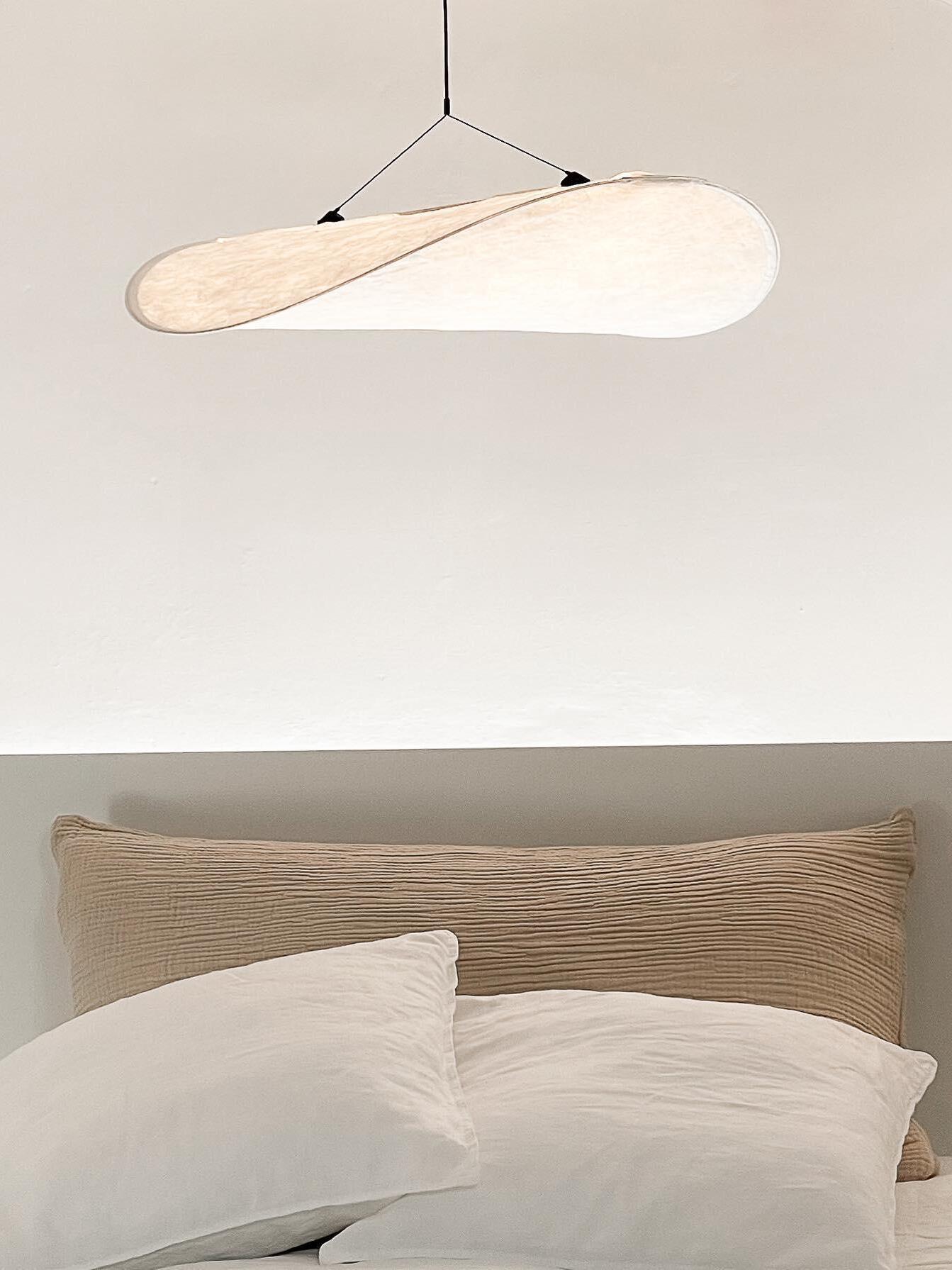 Tense white pendant above a bed headboard