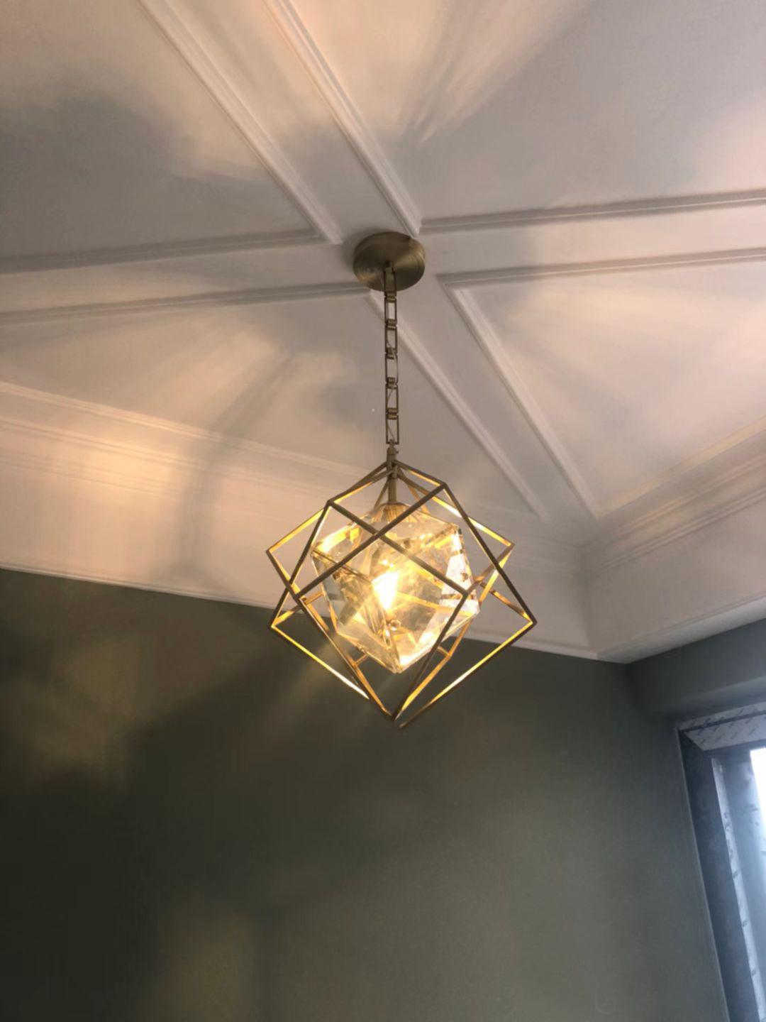Illuminated Epic angular pendant below a pale ceiling beside a green wall and window