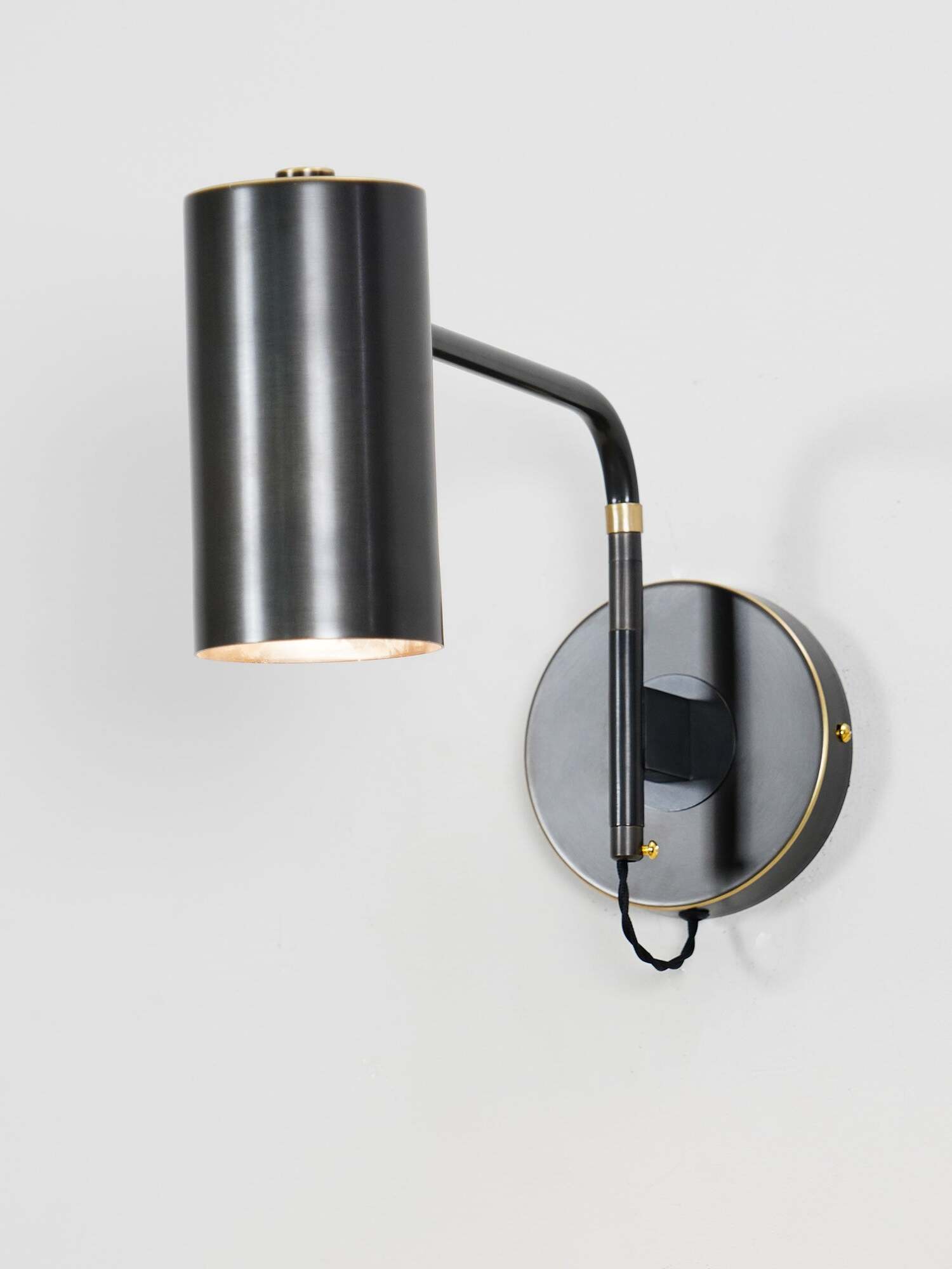 Angled view of black wall light and circular mounting plate