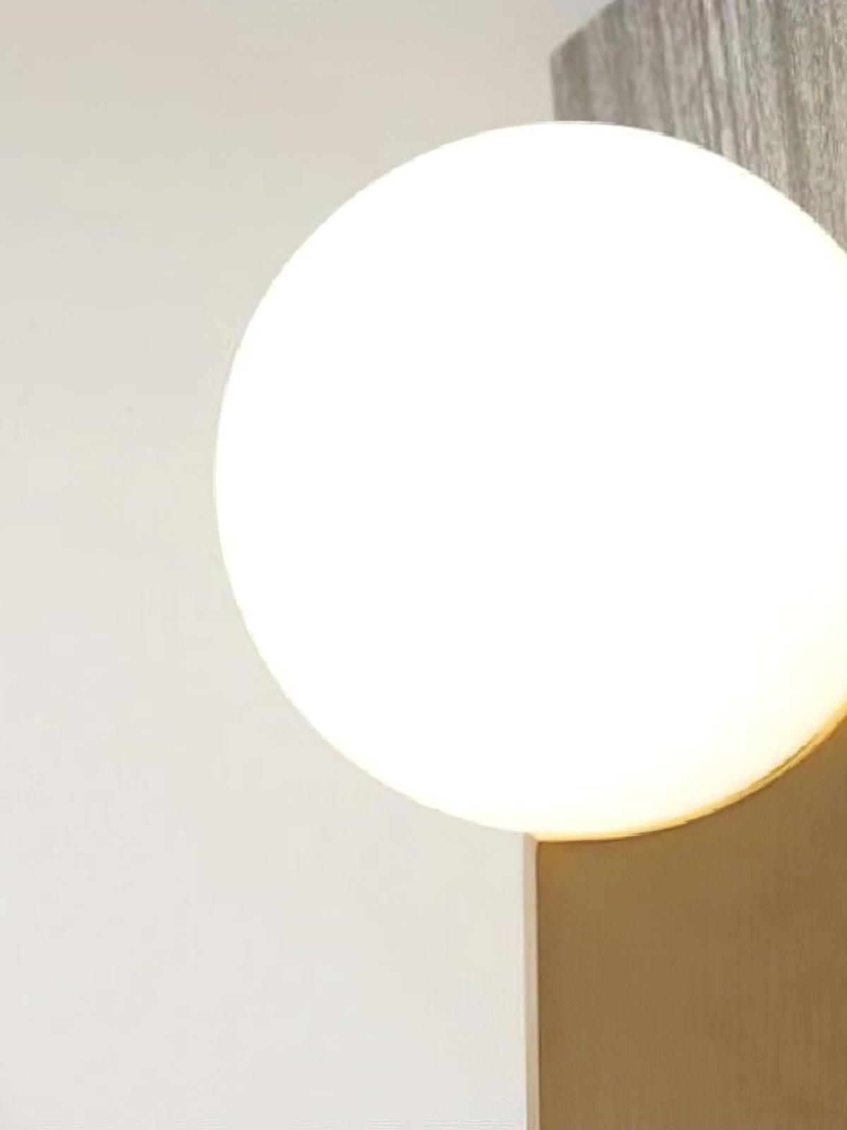 Close view of a bright white globe above the gold-colour blade beside a wall