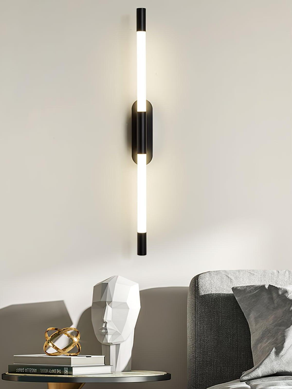 Black Agnes wall light beside a grey headboard and small table with a white vase
