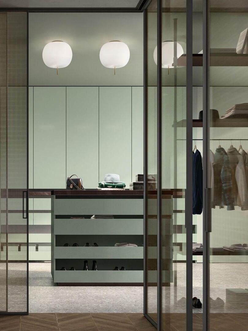 Two white globe-shaped ceiling fixtures above dressing-room cabinets beside glass partitions