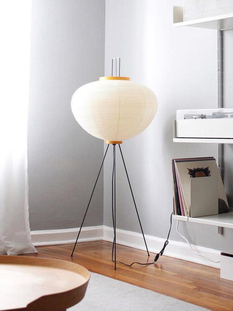Round paper floor lamp beside shelving
