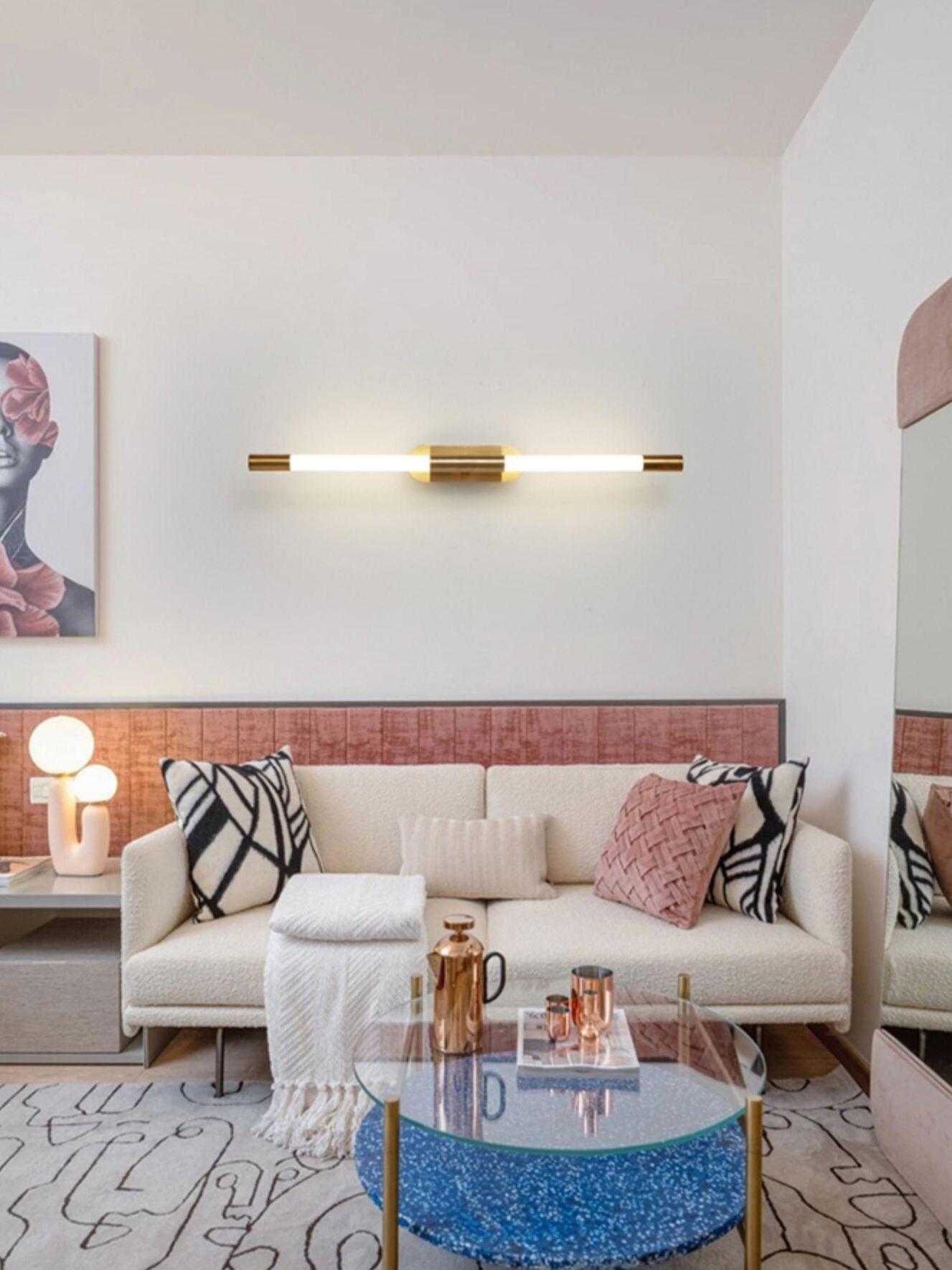 Horizontal gold Agnes wall light above a pale sofa and round blue table