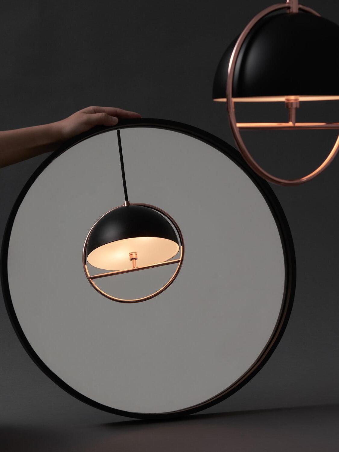 Black ring pendant against round mirror backdrop