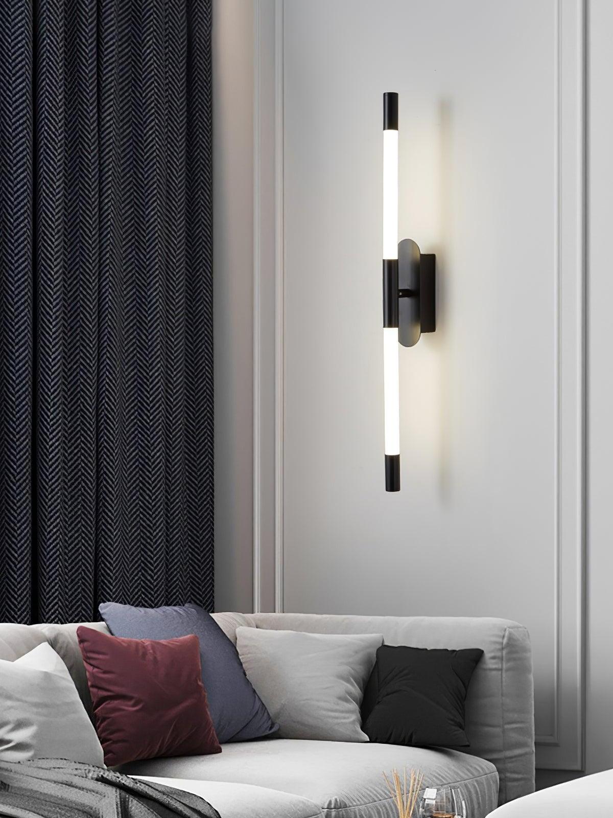 Vertical black Agnes wall light above a sofa beside dark curtains