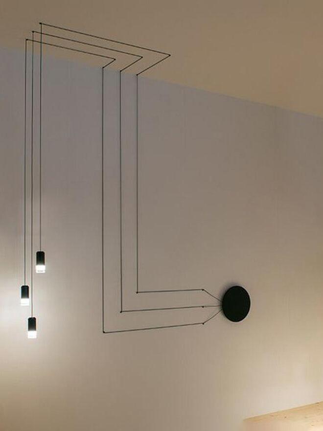 Three lit heads with parallel ceiling and wall cables beside a round black plate