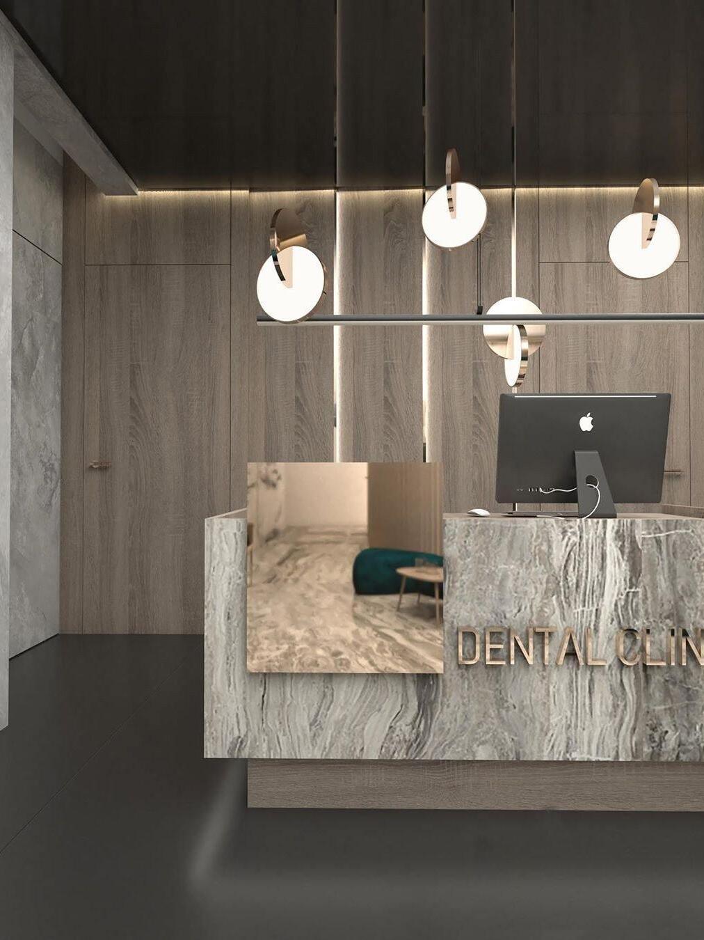 Four gold disc pendant lights above a reception desk with a computer and decorative wall