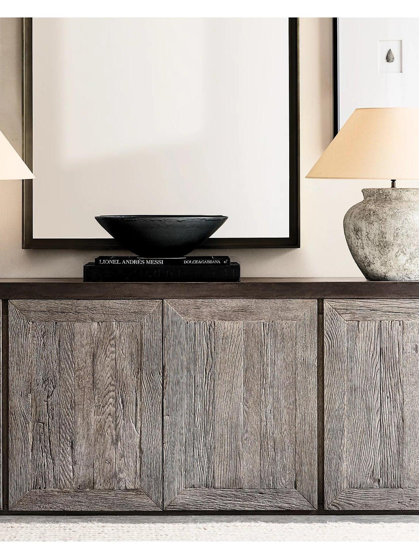 Urn table lamp on wood console beside dark bowl