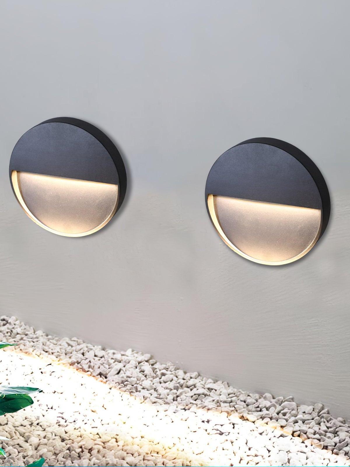 Two round wall lights above pale gravel