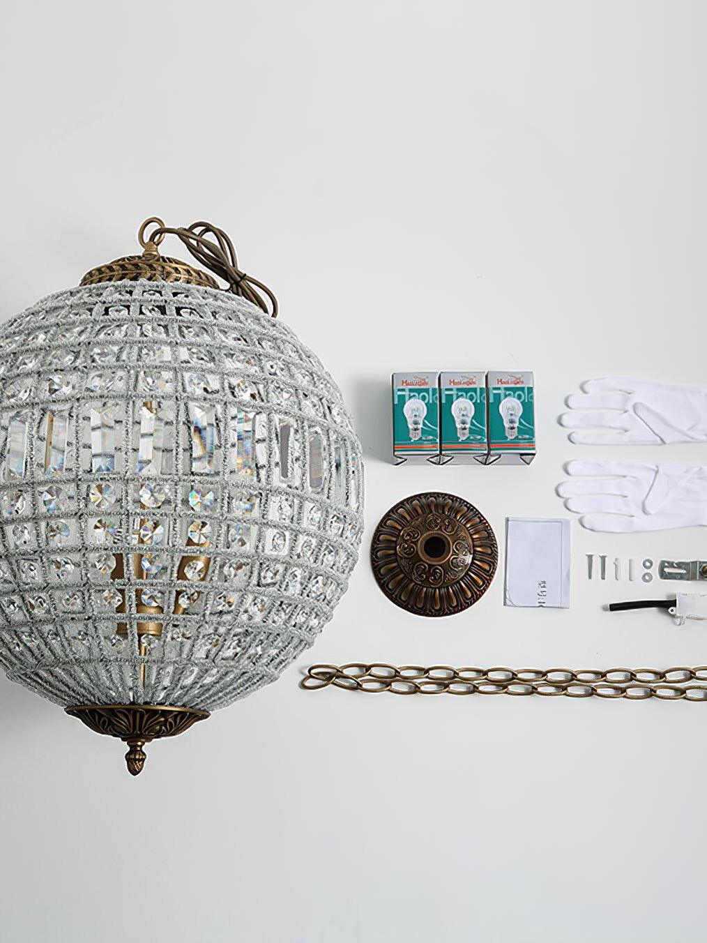 Crystal globe beside three boxed bulbs, gloves, a round canopy, chain, loose hardware and folded paper