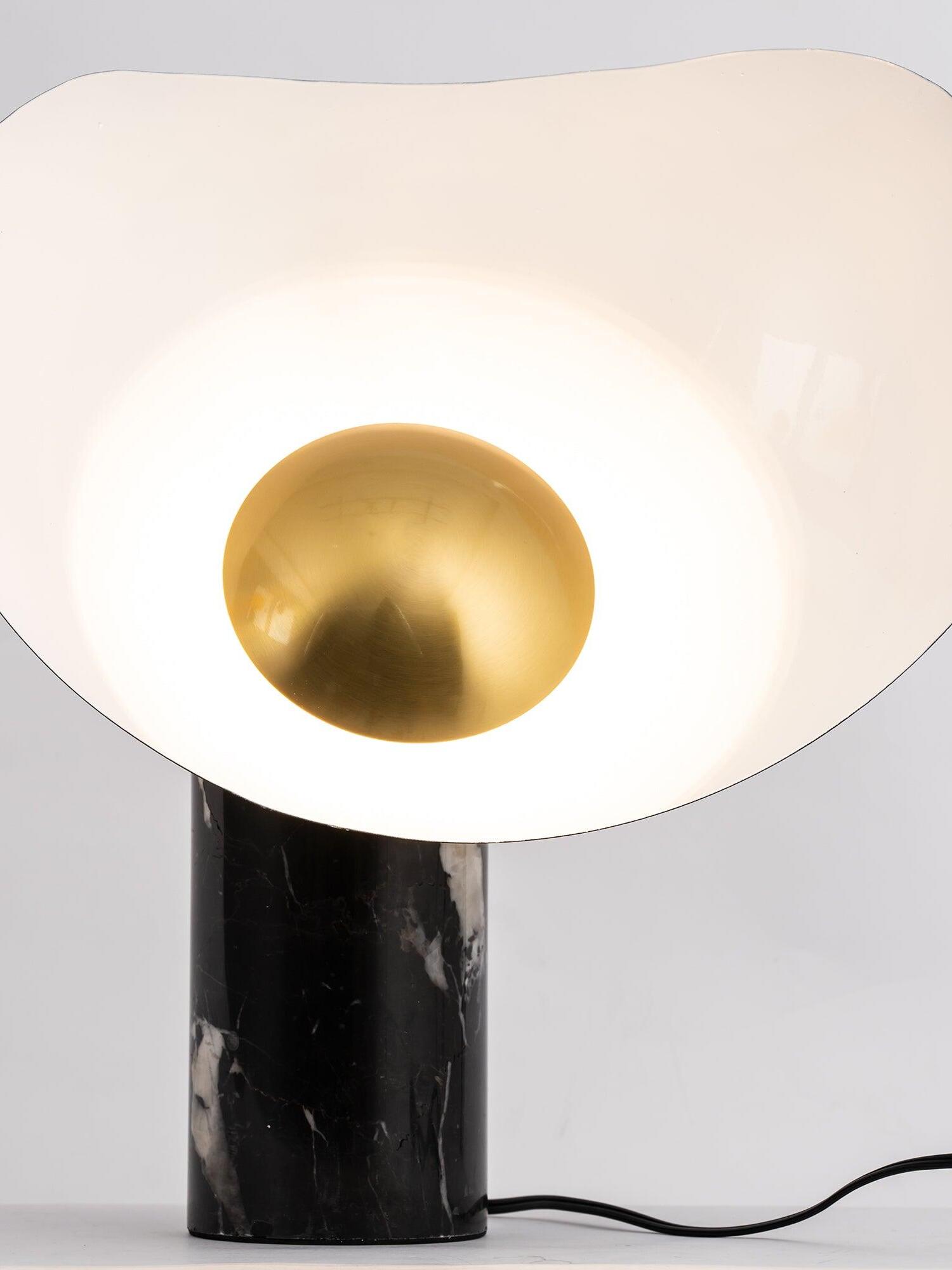 Lit table lamp with white curve and black marble cylinder