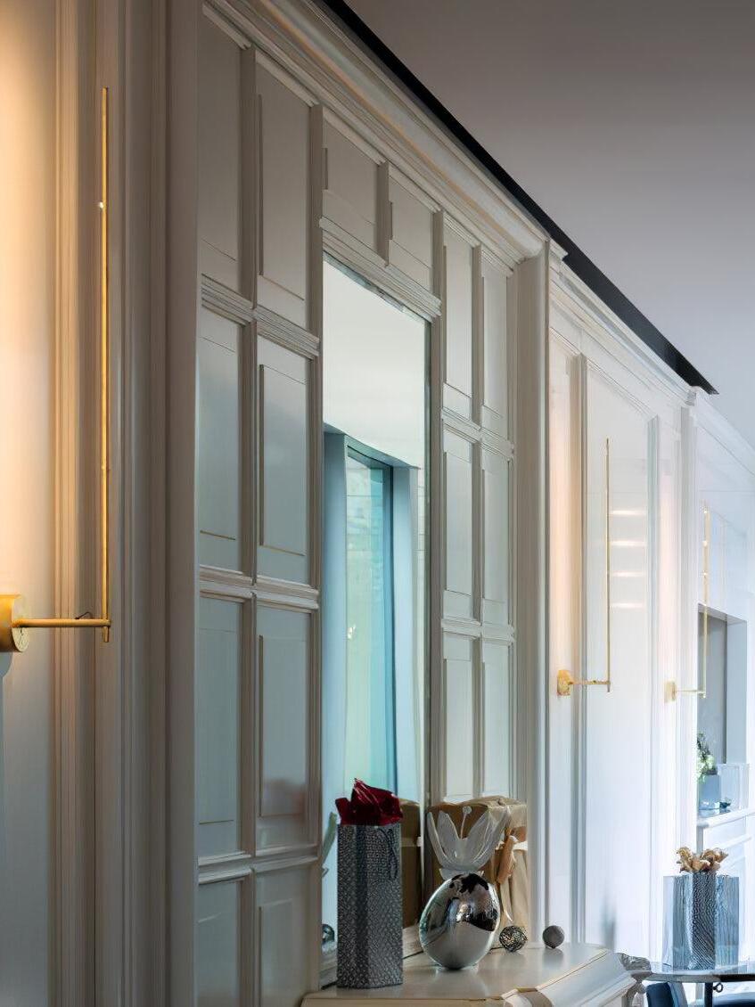 Slim Gold wall light near interior windows
