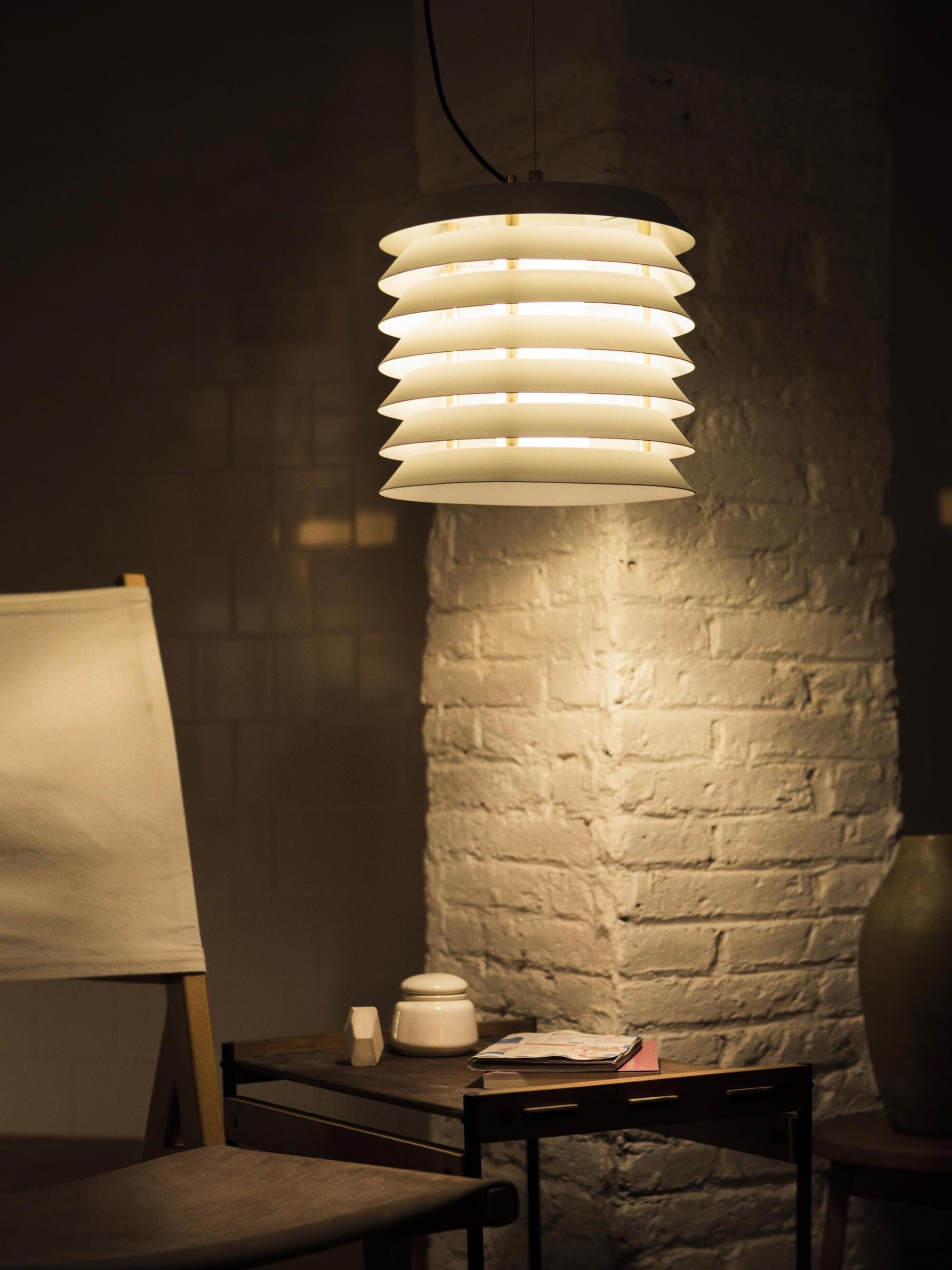Lit stacked pendant near brick column above dark seating corner