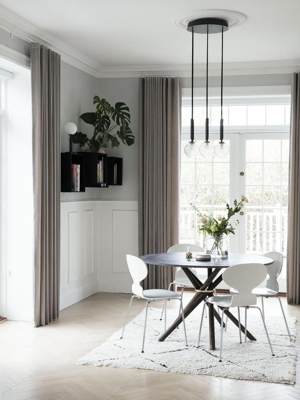 Three textured clear glass globes on black stems below a round canopy above a dining table