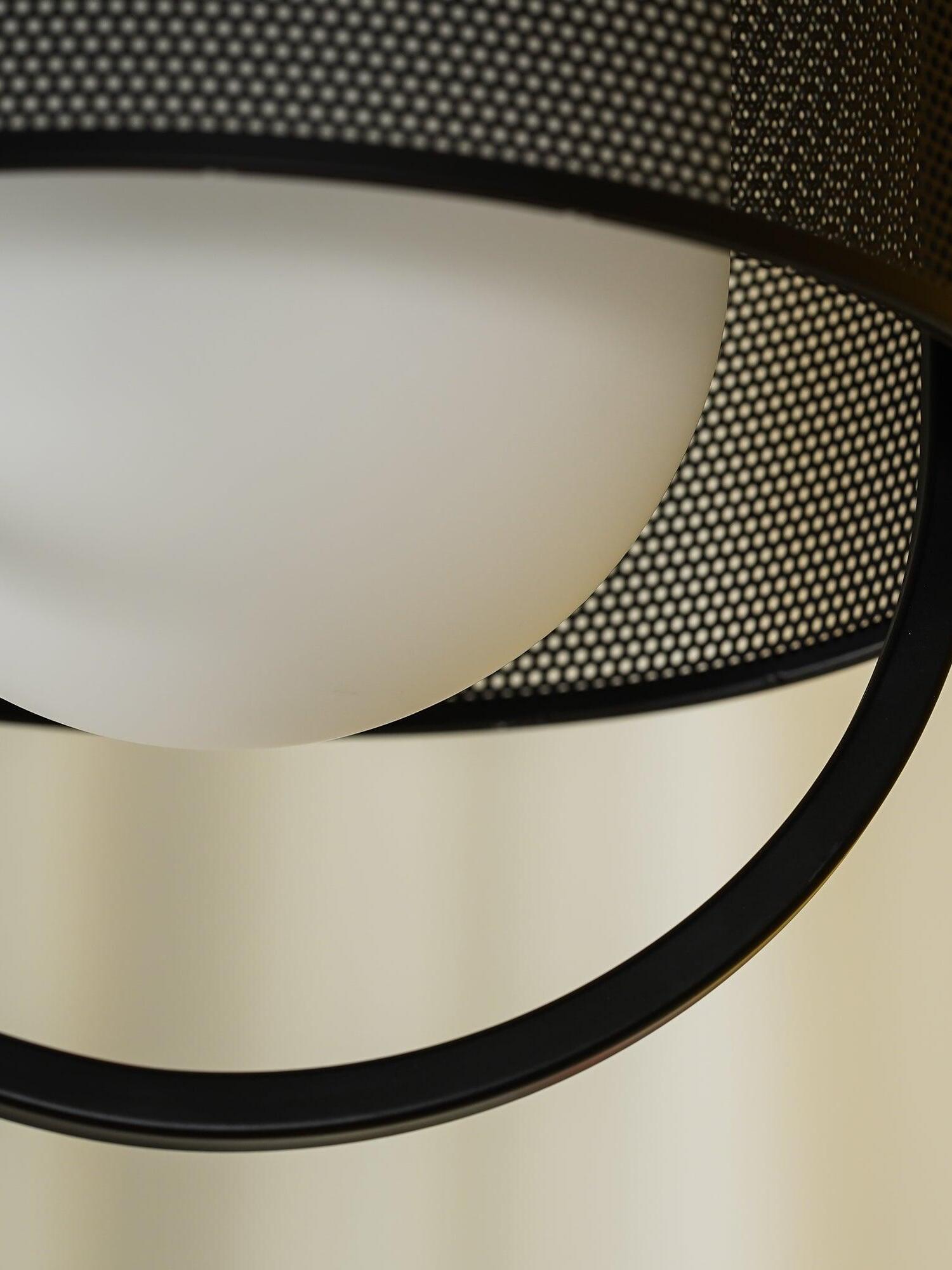 Pale glass diffuser inside curved lower frame of black pendant