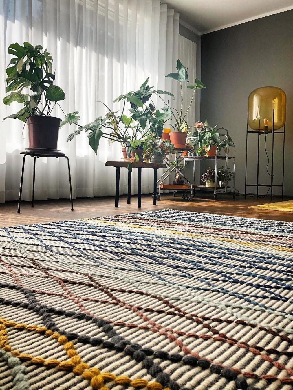 Amber glass floor lamp in a room filled with houseplants and a patterned rug.
