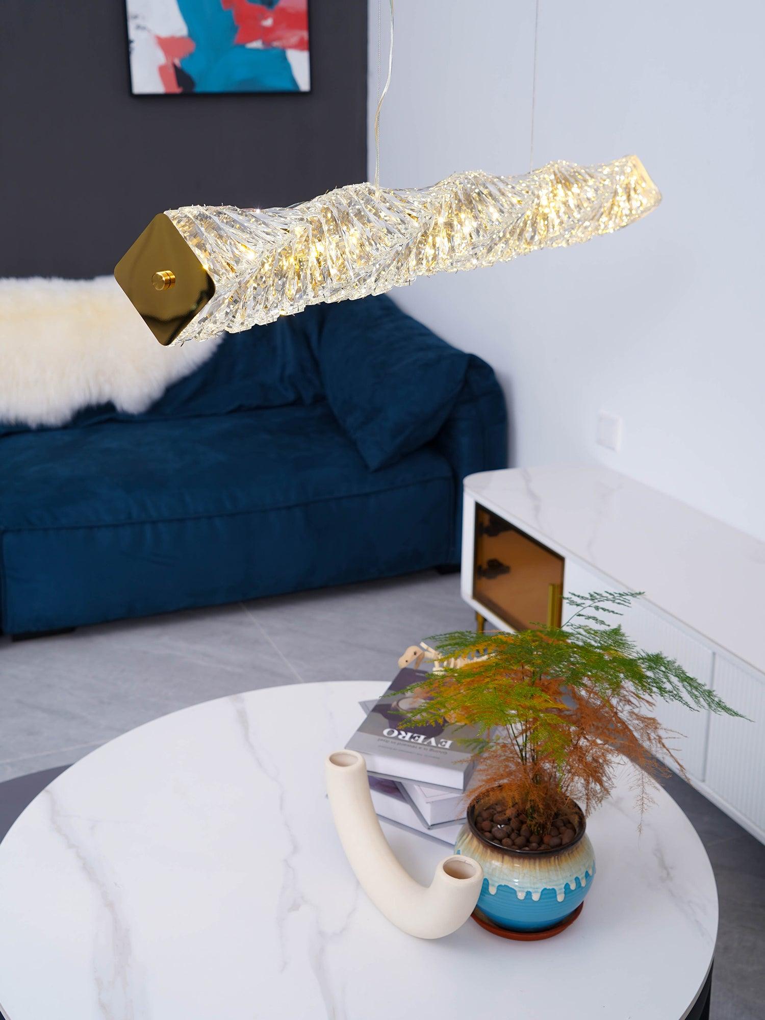 Angled view of the gold end plate and crystal bar near a blue sofa and plant-topped table