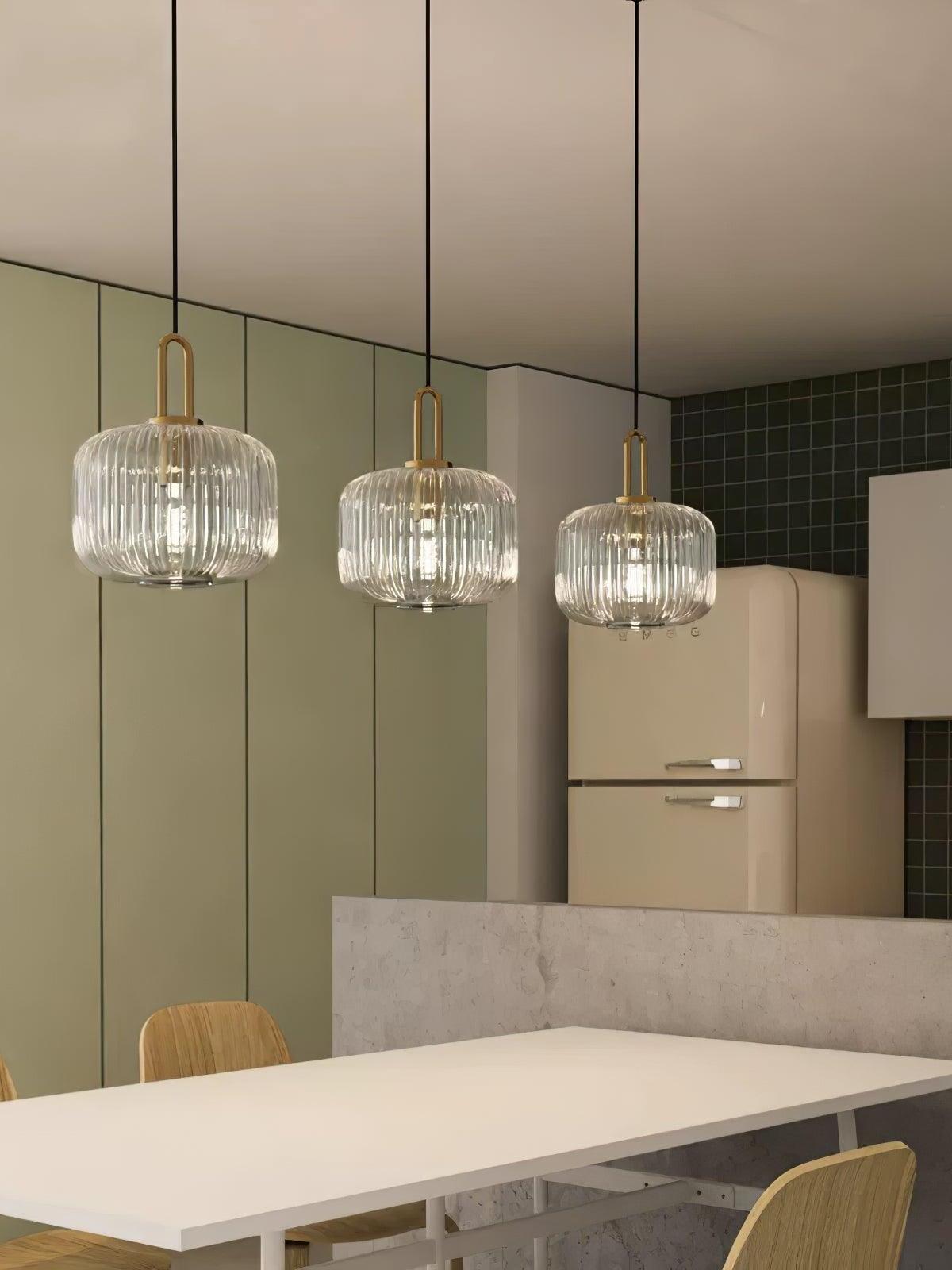 Three separate ribbed-glass pendants above an island