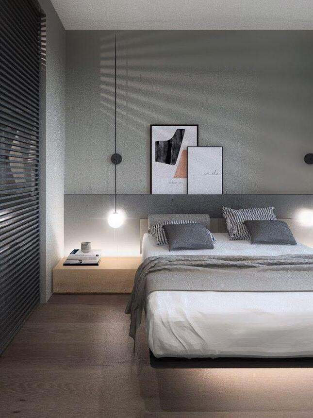 Two separate black rod wall lights beside a grey bed, with framed artwork above the headboard