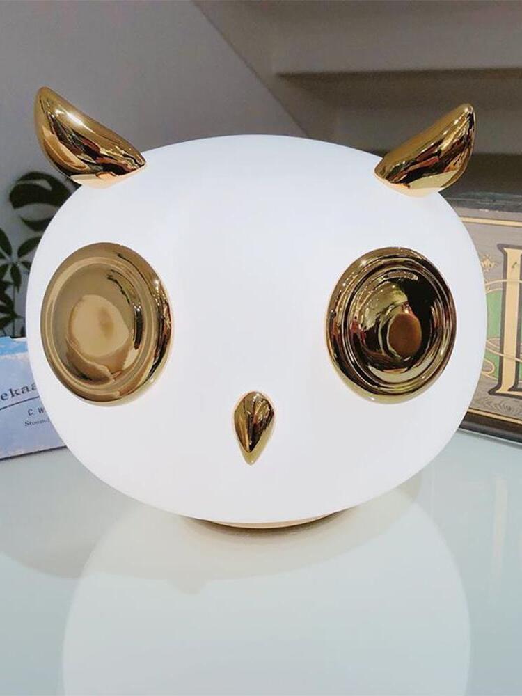 Close white owl glass lamp with reflective gold-tone eyes, beak and pointed ears