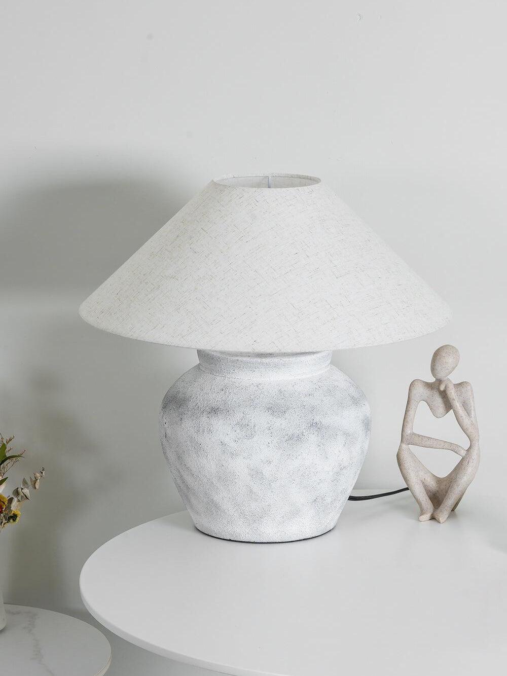 Unlit pale urn lamp with dark cord on round table
