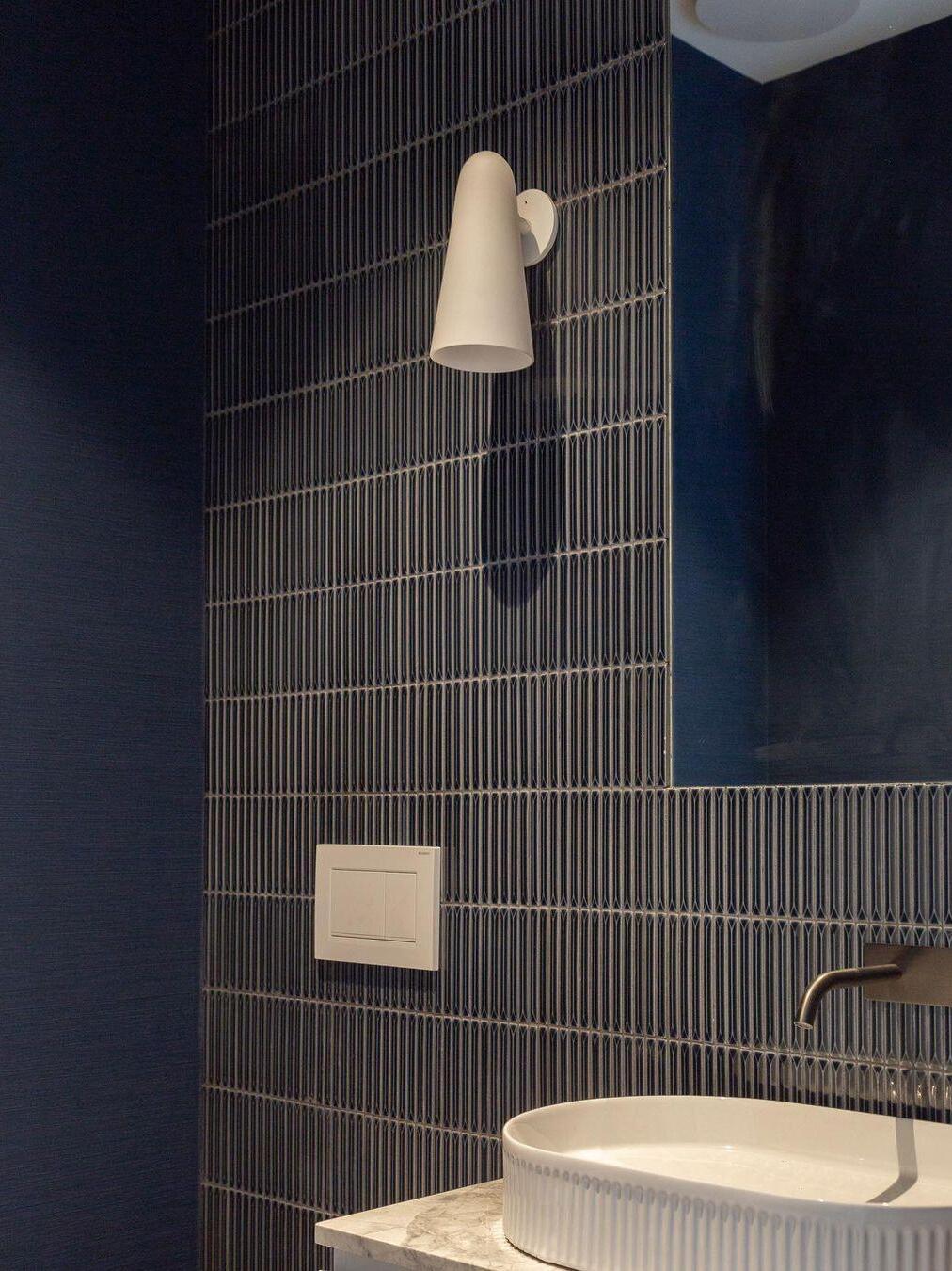 Pale conical shade above a basin against blue tiles