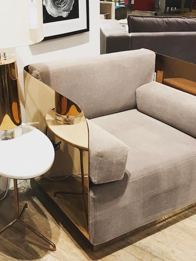 White-shade gold-tone cylinder lamp beside pale sofa and gold-coloured chair frame