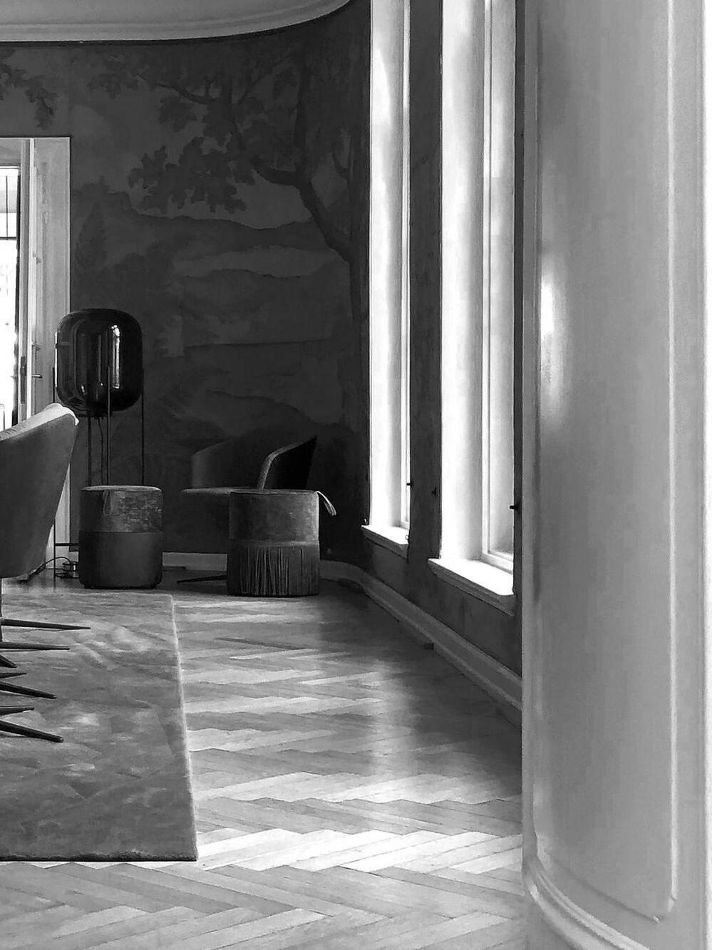 Dark rounded glass lamp beside an armchair in a monochrome room.