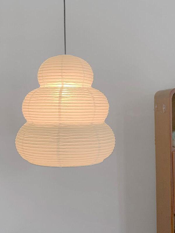 Lit ribbed paper pendant against plain wall
