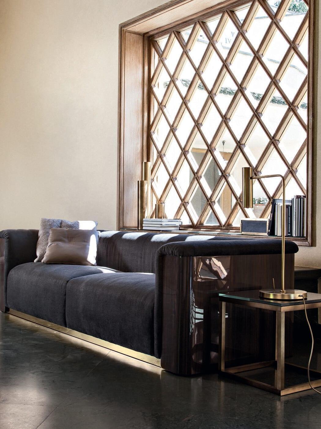 Gold-tone lamp and visible cord on side table beside sofa and lattice window