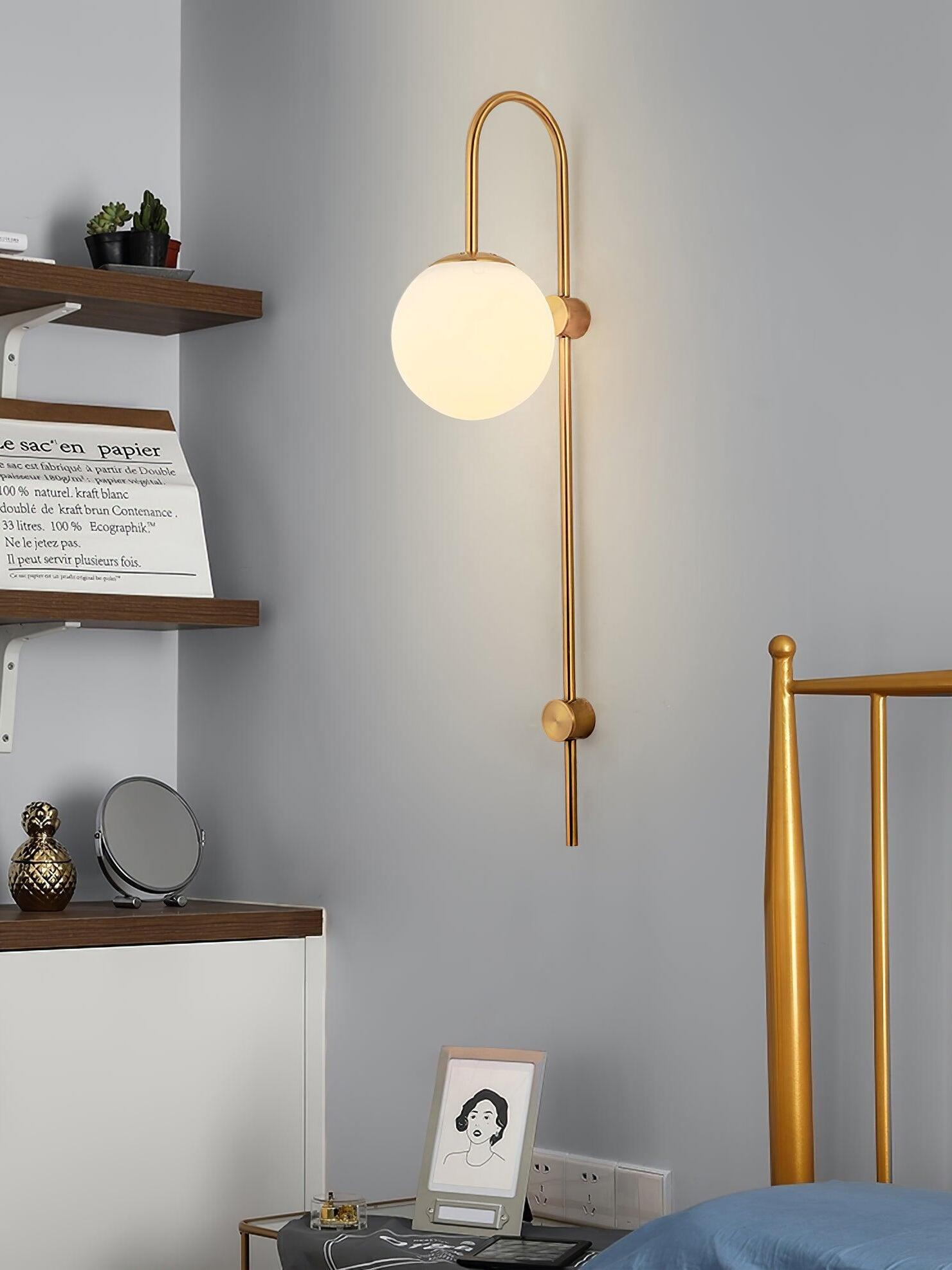 Lit gold wall sconce above bedside shelf